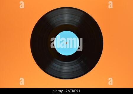 old black vinyl record with blank cyan label centered on orange background Stock Photo