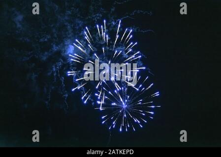 Cheap bluish fireworks against the dark sky. Stock Photo