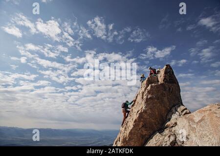Three rock climbers each the summit of a mountain in Tetons, Wyoming Stock Photo
