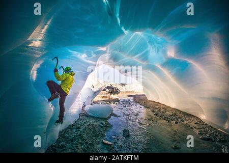 Man ice climbing in cave during luxury adventure tour. Stock Photo