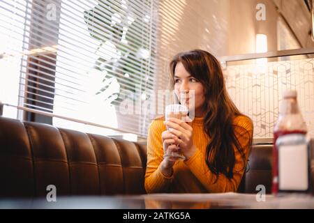 Teenage girl drinking chocolate milkshake in restaurant Stock Photo