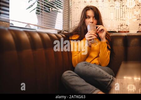 Thoughtful teenage girl drinking chocolate milkshake in cafe Stock Photo