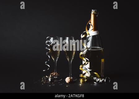 Two glasses of champagne with the bottle against black background. Stock Photo