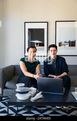 Portrait of confident smiling business coworkers with laptop at table sitting in office Stock Photo
