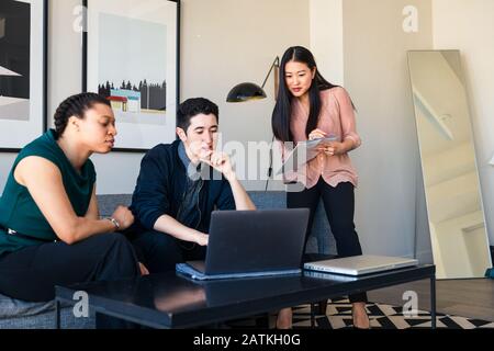 businessman discussing over laptop while female colleague writing on document in office Stock Photo