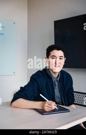 businessman writing with digitized pen on graphics tablet at table in office Stock Photo