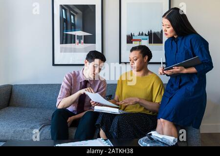 businesswoman discussing over documents with colleagues in office Stock Photo