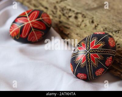 Two romanian traditional easter eggs isolated on white background with wood board, handmade decorated, traditional symbols, eastern europe, text space Stock Photo