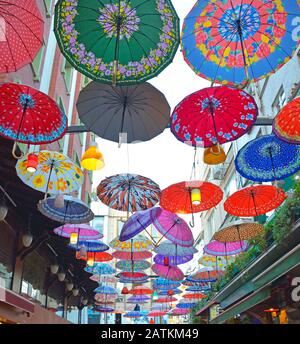 Colourful umbrellas hang from the sky covering a street in the Moda district of Kadikoy on the Asian side of Istanbul, Turkey Stock Photo