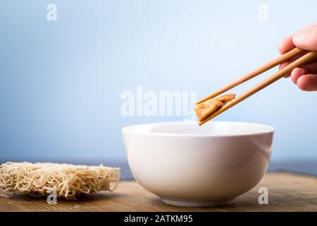 Dried Chinese noodles with meat in the dish. Bamboo chopsticks. Asian cuisine. Stock Photo