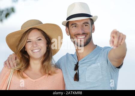 cheerful couple pointing at camera on summer beach Stock Photo