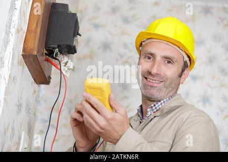 a happy builder measuring voltage Stock Photo