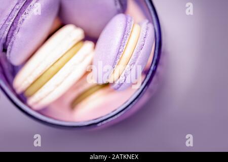 Homemade traditional french violet and yellow macaroons or macarons in a glass on gray background Stock Photo