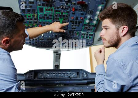two flight engineers talking in cockpit Stock Photo