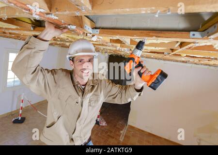 handyman using cordless drill to the ceiling Stock Photo