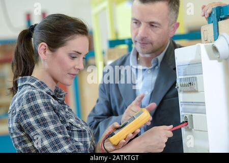 female electrician using multimeter under supervision Stock Photo
