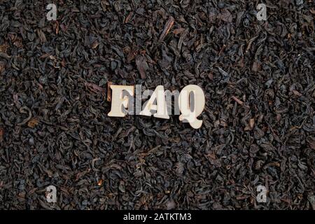 Dry black tea with letters - FAQ. The concept of answers and questions. close up. Stock Photo