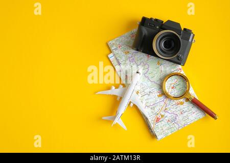 Travel accessories on yellow background. Vintage camera, airplane, magnifying glass and map. Minimalist flat lay style composition, top view. Travel p Stock Photo