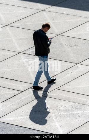 Man looking at smartphone while walking Stock Photo