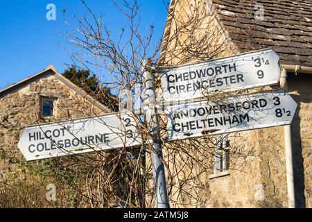 Cotswold village signpost outside a Cotswold stone cottage in winter sunlight. Withington, Gloucestershire, England Stock Photo