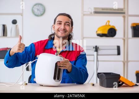 The young male contractor repairing toaster at workshop Stock Photo