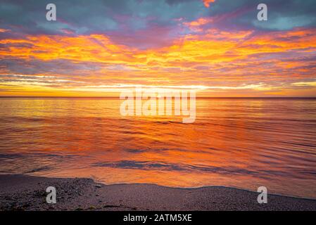 Picturesque sunrise over the sea. Dramatic sky colored in orange and red. Stock Photo