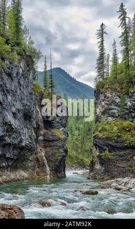 Narrow passage of a mountain river in a clamped canyon. On the cliff is a waterfall from a small stream. River Bilyuty. Eastern Sayan. Buryatia Stock Photo