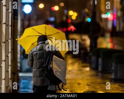 Munich, Germany. 04th Feb, 2020. In the early hours of the morning, a man runs behind a yellow umbrella against the wind that blows through the streets of the city centre. Credit: Peter Kneffel/dpa/Alamy Live News Stock Photo