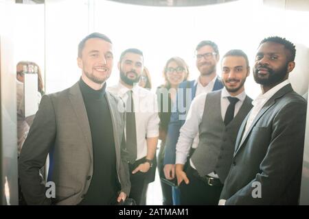 Confident young multi-ethnic specialists of business company standing at entrance and welcoming you Stock Photo