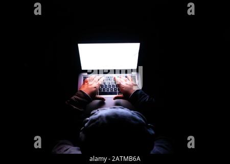 top view of hooded hacker steeling data from laptop  Stock Photo