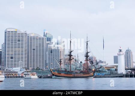 Sydney, Australia - November 22, 2014: Replica of James Cook HMB Endeavor Tall Ship in Darling Harbour with Sydney cityscape on the background on blue Stock Photo