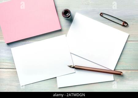 Stationery mock-up with an ink bottle, a nib pen, and a vintage pin. Blank retro fashion greeting cards or invitations, shot from above Stock Photo