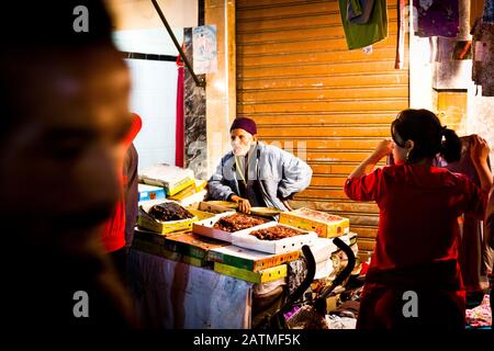 An elderly man at a medina market stall selling dates in Marrakesh, Morocco Stock Photo