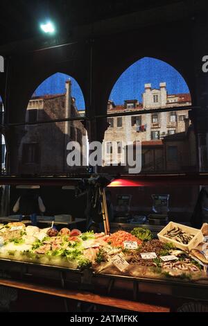 Fresh fish on sale in Campo de la Pescaria, Venice, San Polo seafood market, the Past and Present on display, palazzo, grand canal through open arches Stock Photo