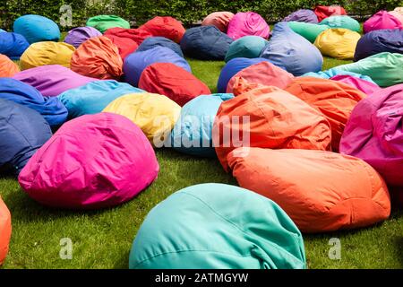 Many colorful bean bag seats to relax on grass outdoors Stock Photo
