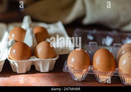 Raw eggs in plastic and cardboard open containers. Close-up. Selective focus. Eye level shooting. Blurred background. Stock Photo