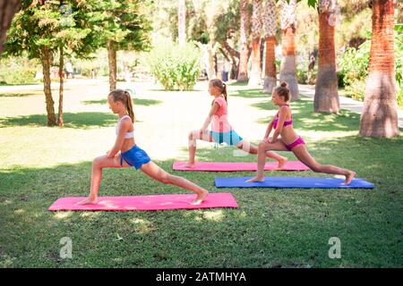 Beautiful young girls working out, exercising, practicing yoga outdoor at the resort. Healthy lifestyle and fitness outdoor concept Stock Photo