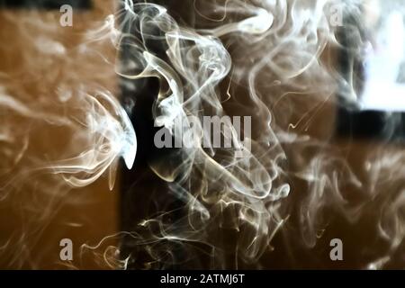 Smoke steam in room lighten by sun light, hazy steam curls for decorative special effect, abstract cigarette smoke background Stock Photo