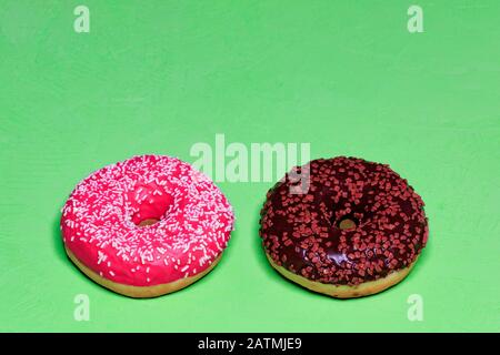 Delicious chocolate and cream donuts on a green rough surface. Stock Photo
