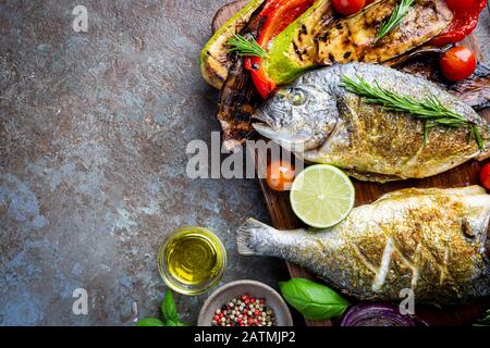 Baked Dorado fish, sea bream with grilled vegetables, herbs and seasonings, top view Stock Photo