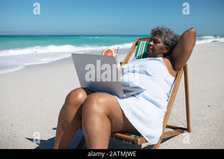 Old woman on laptop at the beach Stock Photo