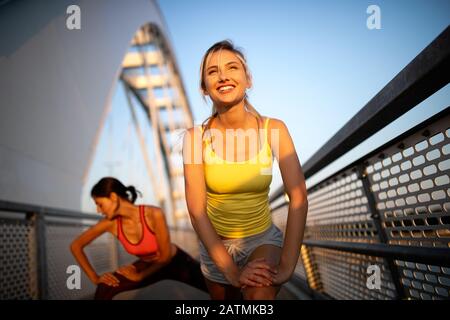 Beautiful happy women friends working out, exercising, running, jogging outdoor. Stock Photo