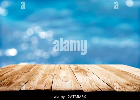 Wooden surface against defocused blue sea background during day. Mock up for display Stock Photo