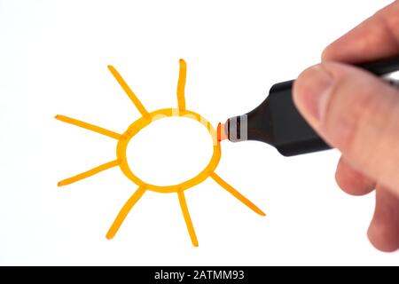 Human hand with felt tipped pen marker, painting drawing sun on a white sheet. Stock Photo