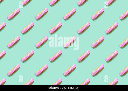 Flat lay with arranged homemade eclairs pattern with blackberries and blueberries on mint color background Stock Photo