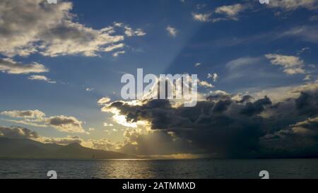 Stormy clouds with sun shining. Dramatic thunderstorm cloudscape with large, building clouds, natural rainy dark sky background. Stock Photo