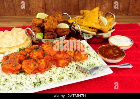 Chicken curry meal with rice and a selection of sides and dips Stock Photo