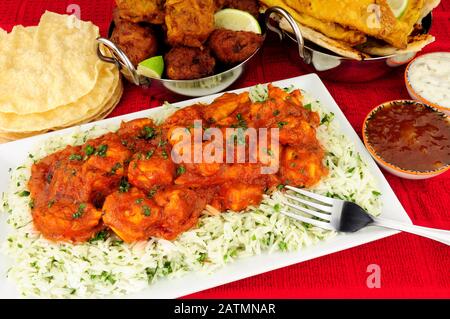 Chicken curry meal with rice and a selection of sides and dips Stock Photo