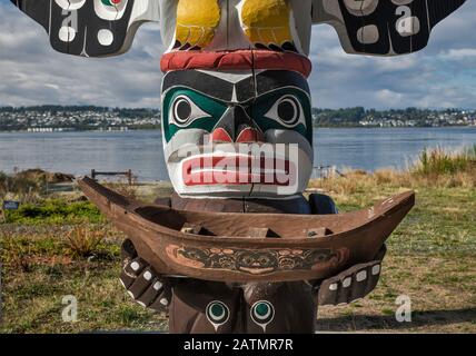 Figure of Wise Man holding a canoe, totem pole at shelter in Nuyumbalees Native Garden in Cape Mudge village, Quadra Island, British Columbia, Canada Stock Photo