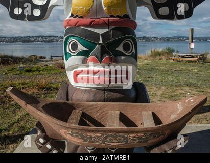 Figure of Wise Man holding a canoe, totem pole at shelter in Nuyumbalees Native Garden in Cape Mudge village, Quadra Island, British Columbia, Canada Stock Photo